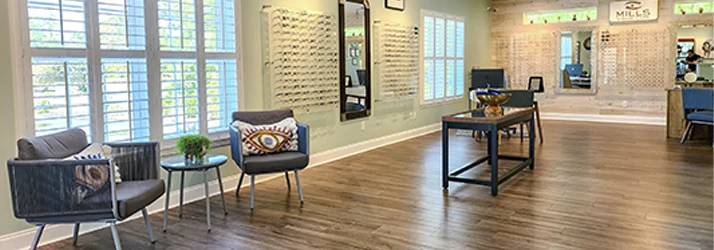 Spacious showroom with chairs, small tables, large windows, wall mirrors, display shelves, and wood flooring.